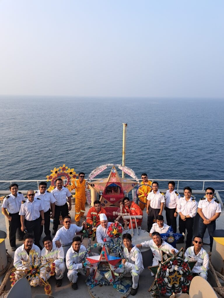 seafarers standing on ship at sea holding colourful christmas lanterns made as part of contest